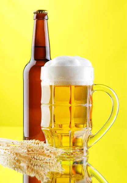 Пивная кружка и бутылки на желтом фоне — стоковое фото