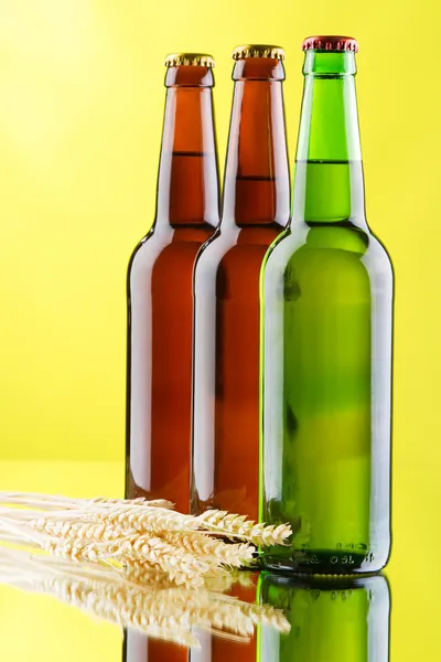 Taza de cerveza y botella sobre fondo amarillo — Foto de Stock