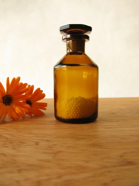 Flores de caléndula y píldoras homeopáticas en frasco de medicina —  Fotos de Stock