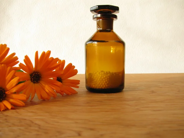 Marigold flowers and homeopathic pills in medicine bottle — Stock Photo, Image