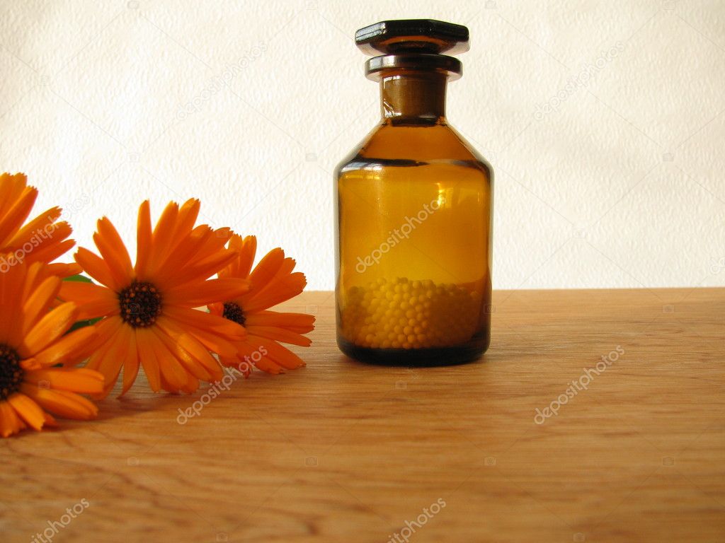 Marigold flowers and homeopathic pills in medicine bottle
