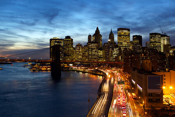 Busy traffic in New York City Manhattan with Brooklyn Bridge at dusk