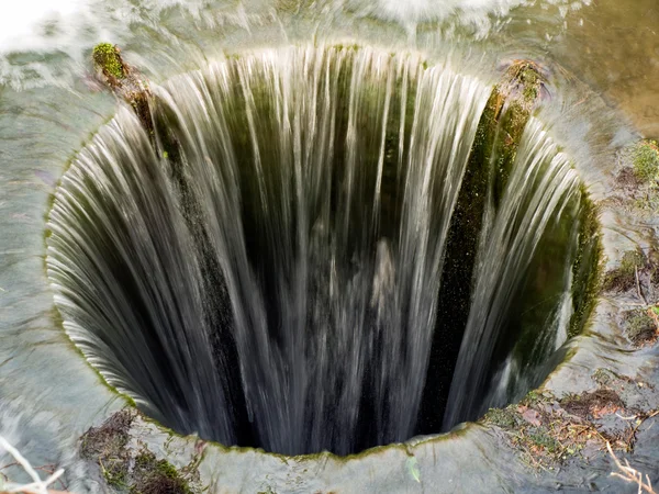 Глибоко бездонну яму з водою тече — стокове фото
