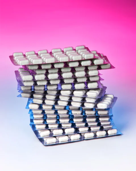 Pilha de pílulas contra fundo colorido — Fotografia de Stock