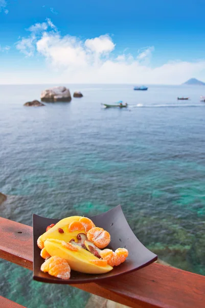 Tallrik med exotiska frukter mot havsutsikt — Stockfoto