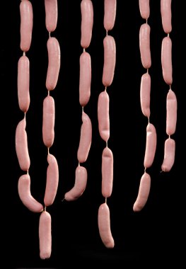 Bunches of freshly prepared raw sausages hanging clipart