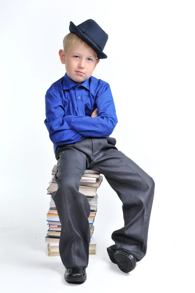 折叠了手，坐在书堆上的男孩 — 图库照片