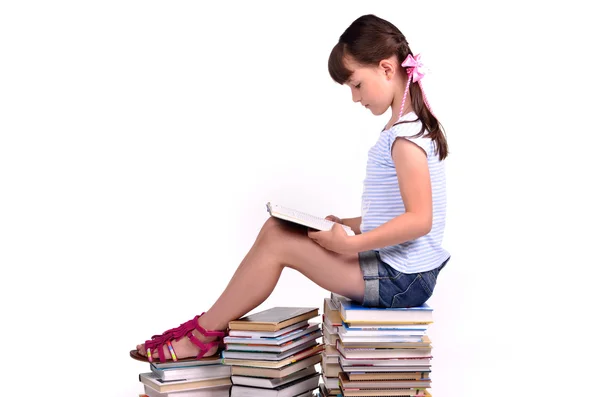 Κορίτσι που κάθεται σε ένα μεγάλο σωρό από βιβλία και την ανάγνωση — Φωτογραφία Αρχείου