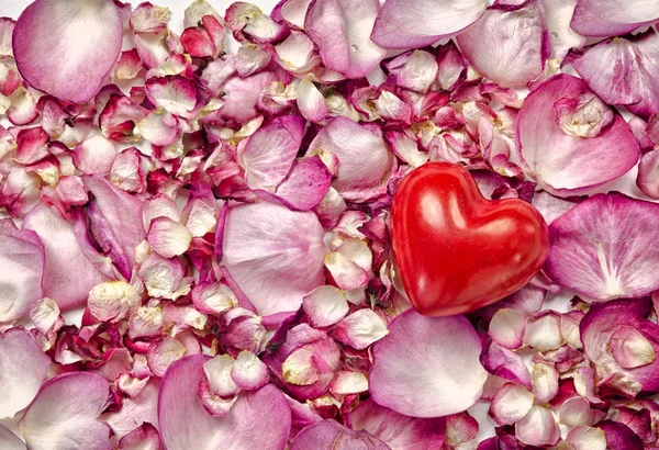 Розовые лепестки роз фон с сердцем — стоковое фото