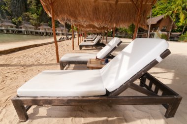 A row of beach beds at the shore clipart