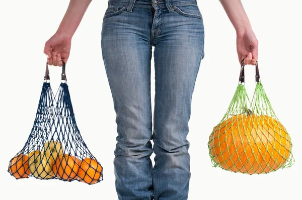Primer plano de una mujer con jeans llevando frutas amarillas — Foto de Stock