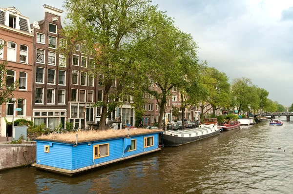 Típico canal de Amsterdam con barco casa azul y barcos —  Fotos de Stock