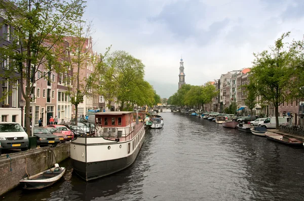 Canal típico de Amsterdã com e barcos estacionados ao longo dele — Fotografia de Stock