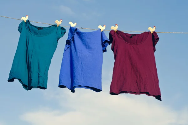 A group of female t-shirts on a string against blue sky — Stock Photo, Image