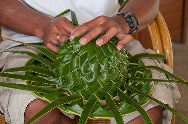 Woman making sunhat of palm leaves clipart