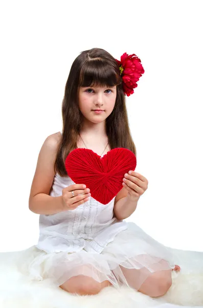Brunette girl wearing white dress holding red heart in her hands — Stock Photo, Image
