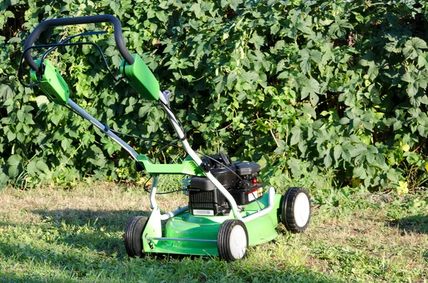 Lawn mower against grass — Stock Photo, Image