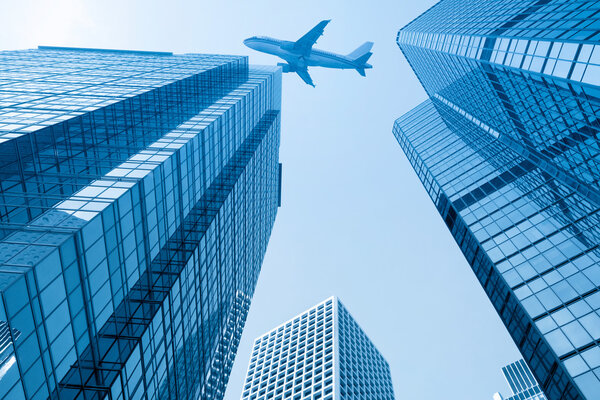 Modern glass building with airplane under the sky in hong kong