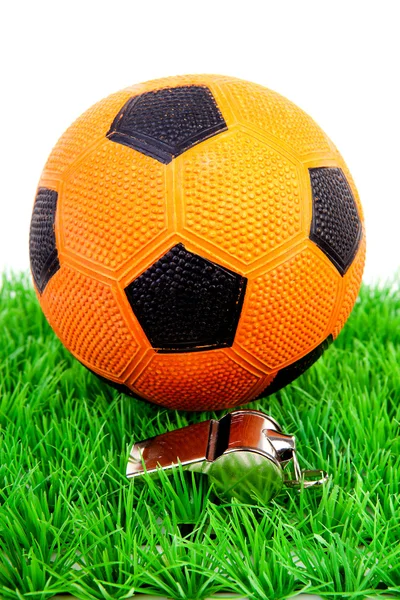 Bola de fútbol naranja y flauta sobre hierba — Foto de Stock
