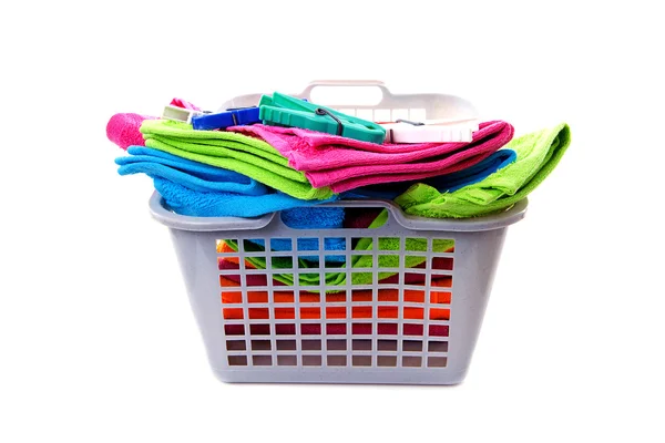 Cesta de lavanderia cheia de toalhas coloridas e cavilhas — Fotografia de Stock