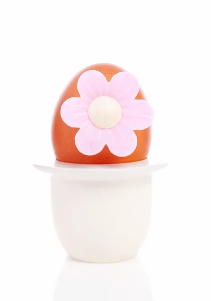 Одно куриное яйцо с розовым цветком в держателе — стоковое фото