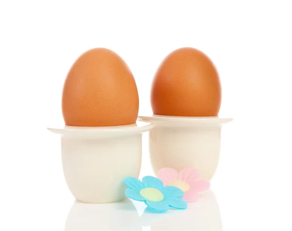 Two chicken eggs in holder with flowers — Stok fotoğraf