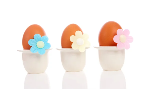 Three chicken eggs in holder with flowers — Stock Photo, Image