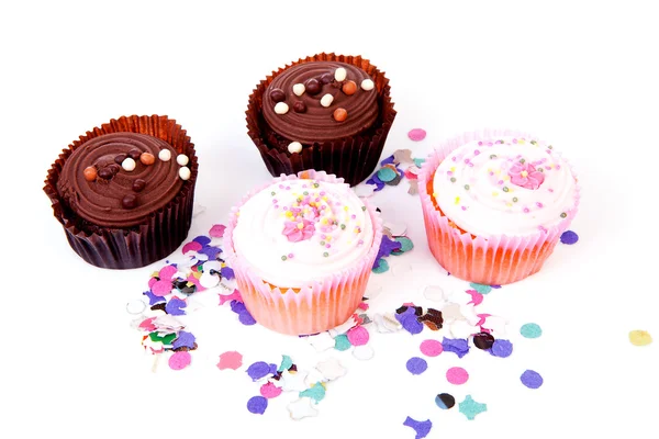 Four delicious cupcakes and colorful confetti — Stock Photo, Image