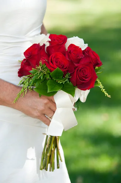 Bride holding red rose bouquet — Stock Photo, Image