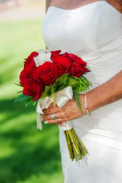 Bride holding red rose bouquet — Stock Photo, Image