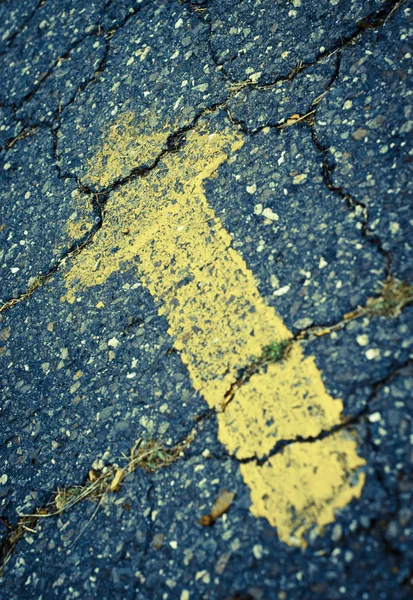 破裂路面上黄色画的箭头 — 图库照片