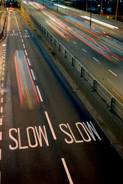 Tráfego rodoviário turvo à noite com aviso cantar "lento " — Fotografia de Stock