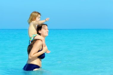 Happy child with her mother on the beach clipart