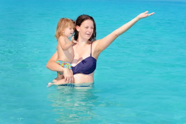 Счастливый ребенок с мамой на пляже — стоковое фото