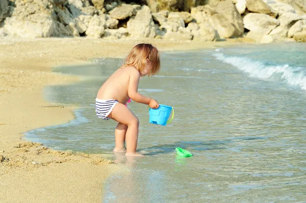 Счастливый ребенок на пляже играет со своими игрушками — стоковое фото