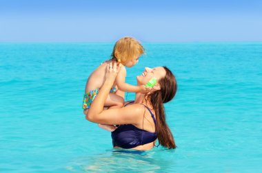 Happy child with her mother on the beach clipart