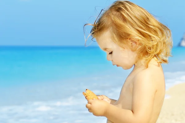 Happy toddler girl holding her snack at the famous Egremni beach — Stock Photo, Image