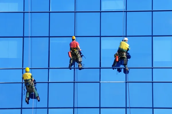 Lavadoras lavar a fachada de vidro do arranha-céu moderno — Fotografia de Stock