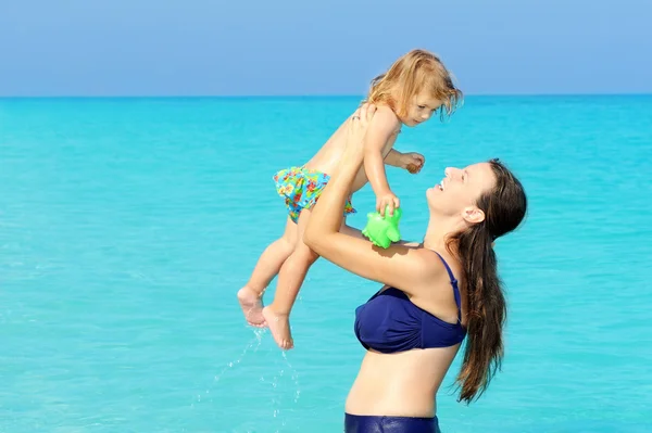 Criança feliz com sua mãe na praia — Fotografia de Stock