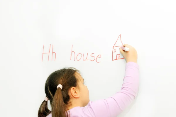 Glimlachend schoolmeisje leren schrijven brief h — Stockfoto