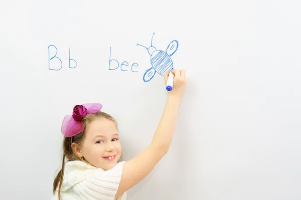 Smiling schoolgirl learning to write letter B — Stock Photo, Image