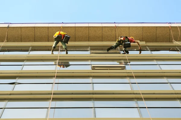 Lavadoras lavar a fachada de vidro do arranha-céu moderno — Fotografia de Stock