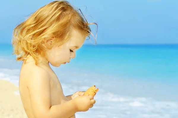Glada barn girl håller hennes mellanmål på berömda egremni stranden — Stockfoto