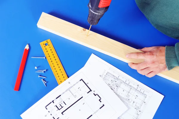 Carpenter`s hand with blueprints and drill machine — Stock Photo, Image