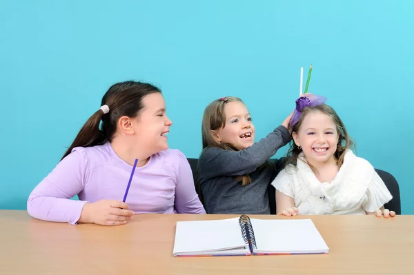 Fröhliche Schulmädchen, die im Klassenzimmer Witze machen — Stockfoto