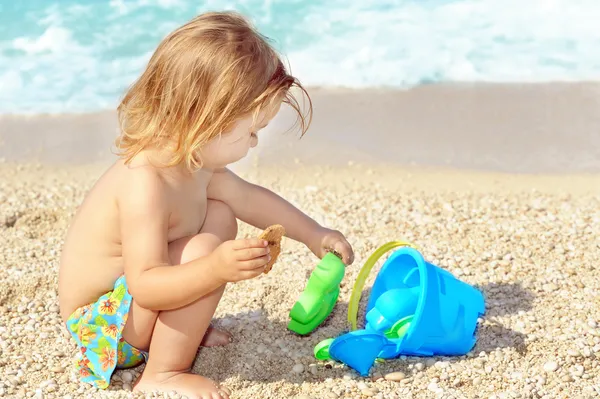 Criança feliz na praia brincando com seus brinquedos — Fotografia de Stock