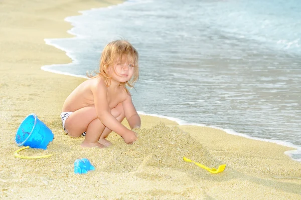 Lyckligt barn på stranden leker med hennes leksaker — Stockfoto