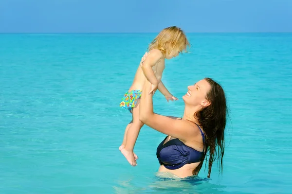 Glada barn med sin mor på stranden — Stockfoto