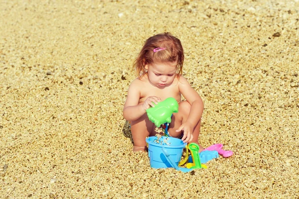 Счастливый ребенок на пляже играет со своими игрушками — стоковое фото