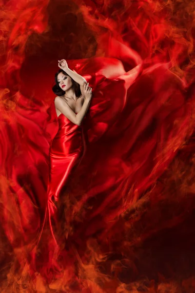 Hermosa mujer en rojo ondeando vestido de seda como una llama de fuego . —  Fotos de Stock